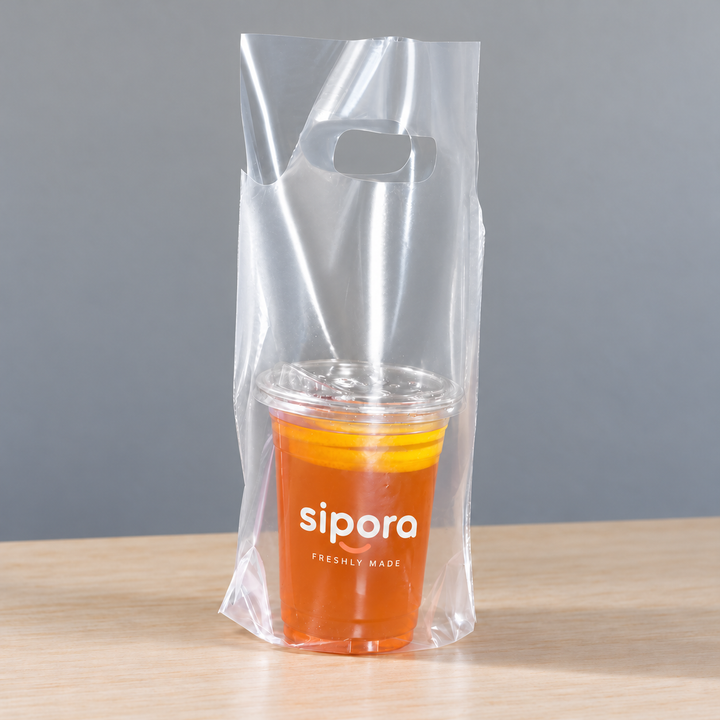 Clear PE single-cup takeaway bag with die-cut handle holding a lidded orange lemon tea.