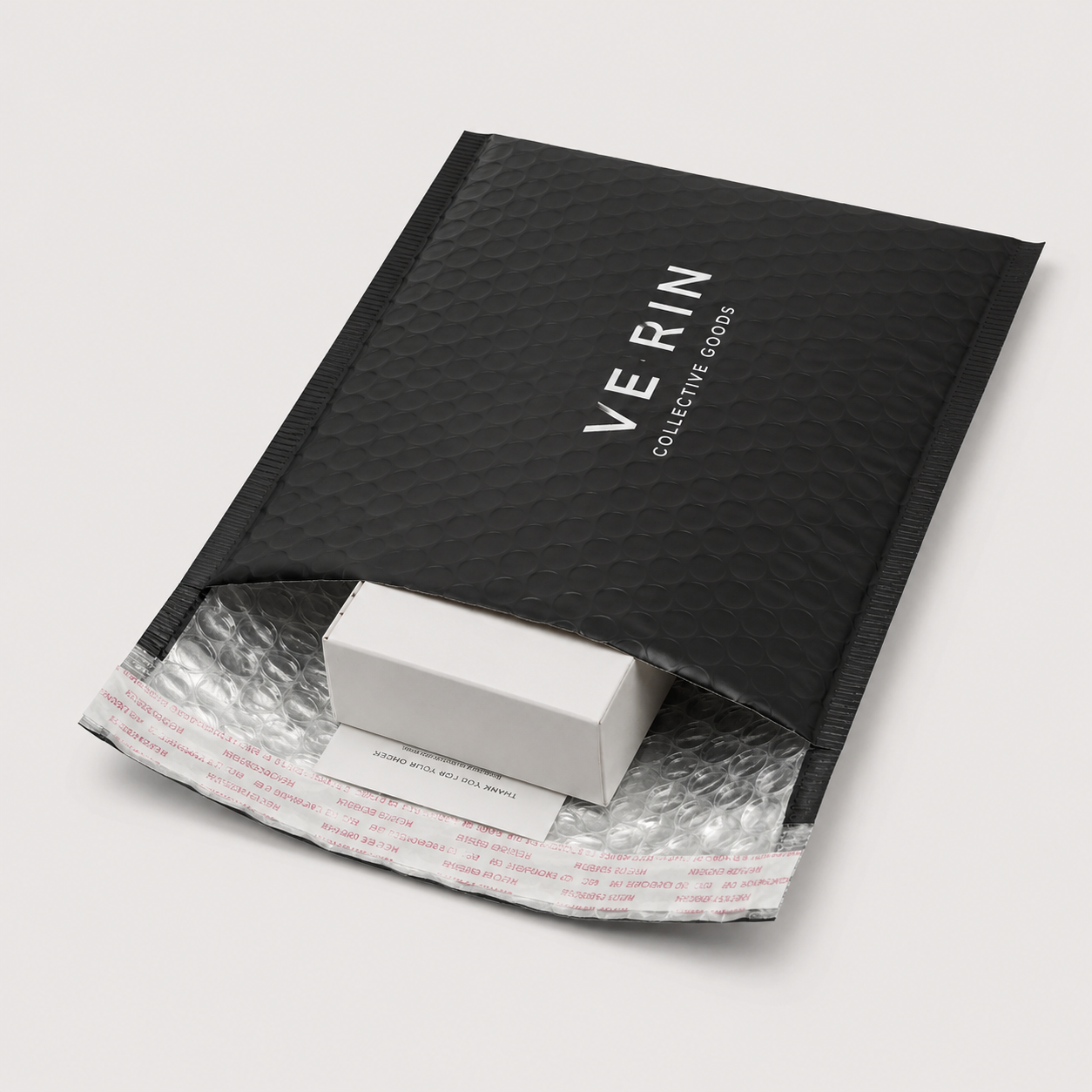 Black matte bubble mailer opened with a small box, showing waterproof padded bubble lining for ecommerce shipping.