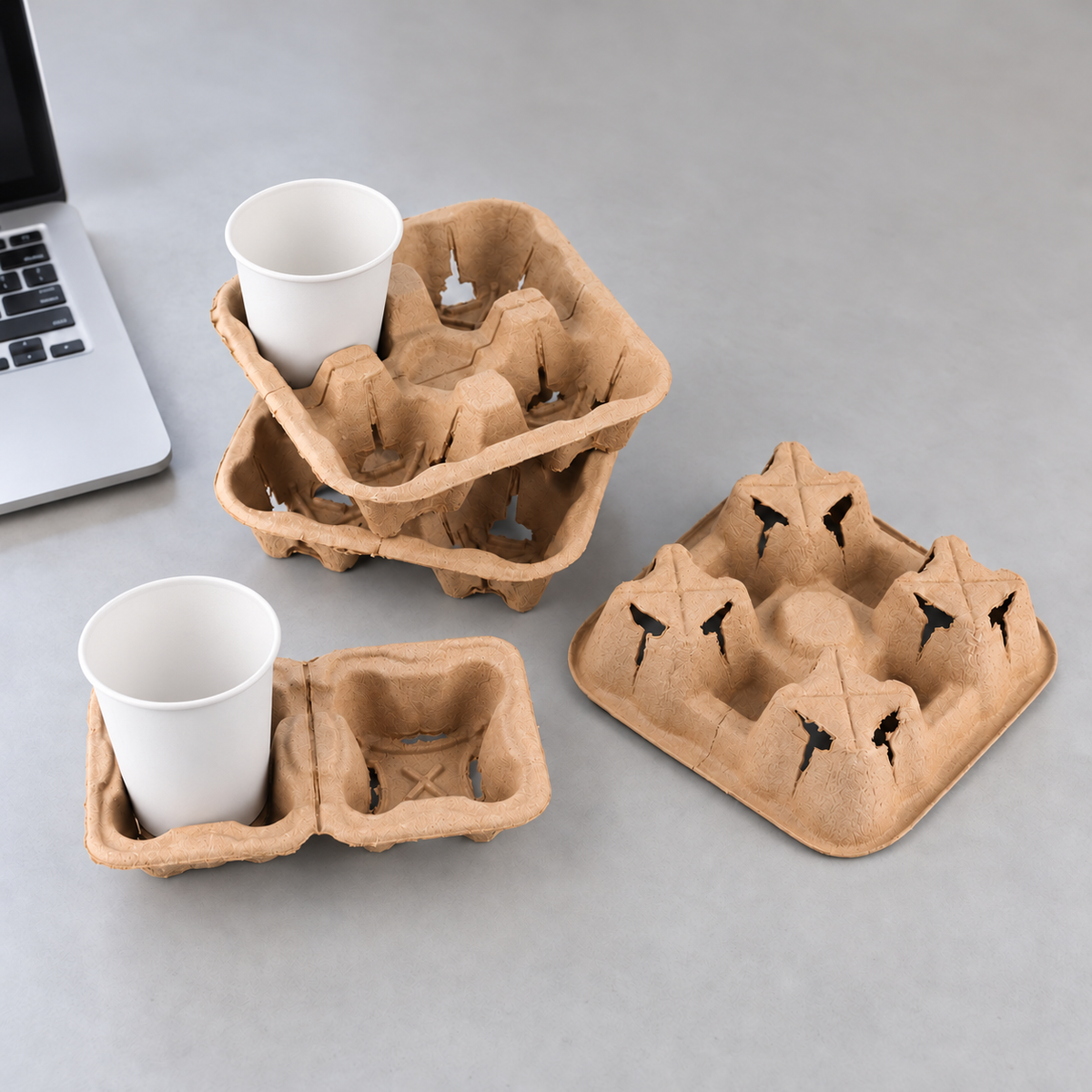 Two-cup molded pulp drink carrier holding a white paper cup, with four-cup carriers alongside